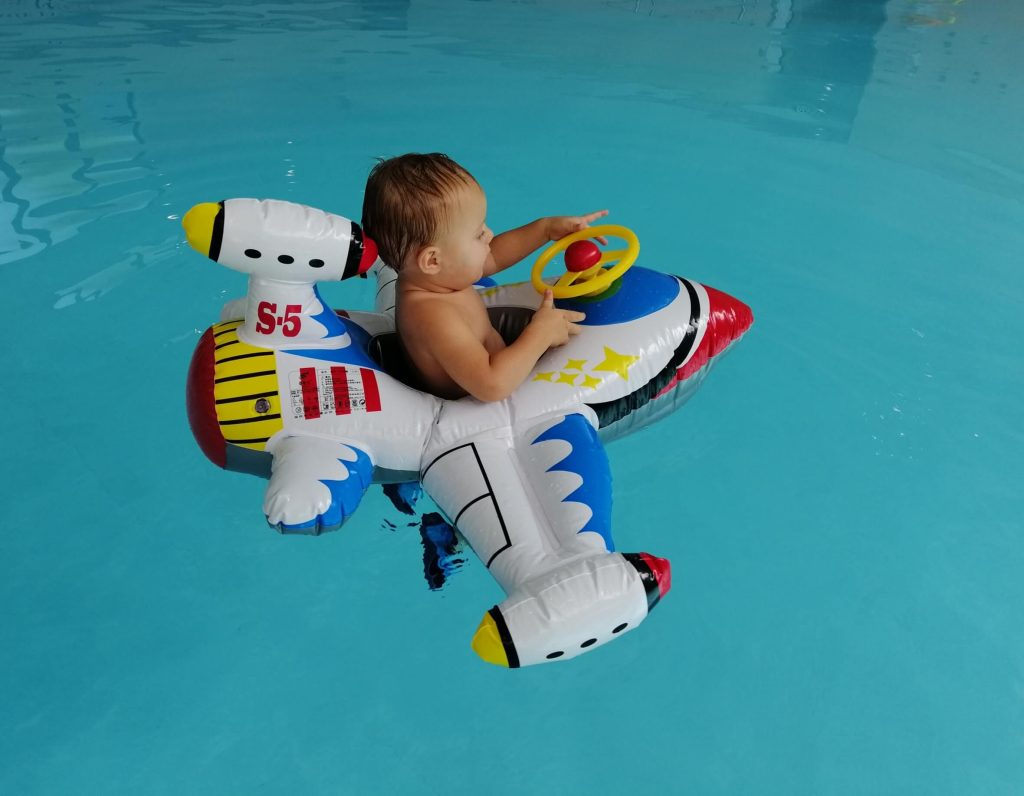 Kleinkind auf Schwimmtier beim Kleinkinderschwimmen